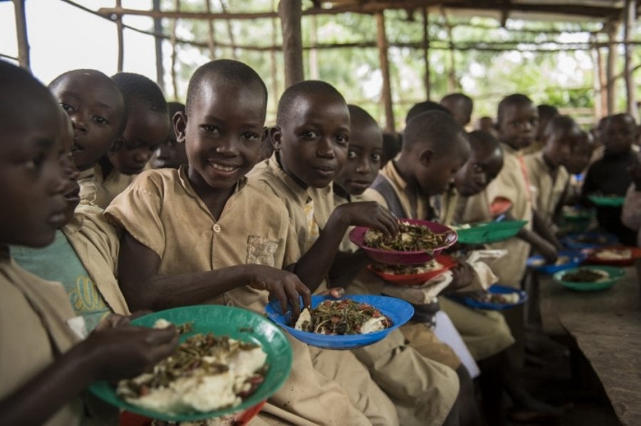 Black children smiling and eating a meal from plastic plates