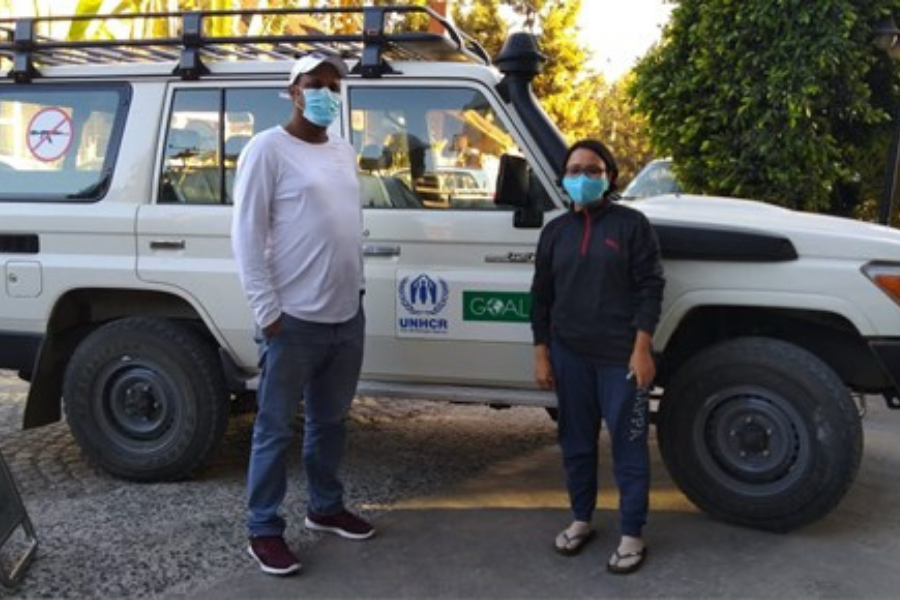 Ritu is with a colleague standing in front of a white jeep. They are both wearing face masks and socially distanced.