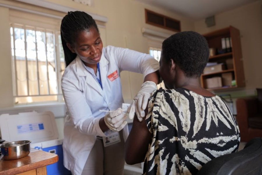 Nurse administering vaccine in arm of clinical trial participant in Uganda