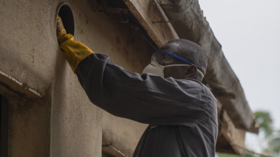 Man installing eave tubes for malaria control in Africa