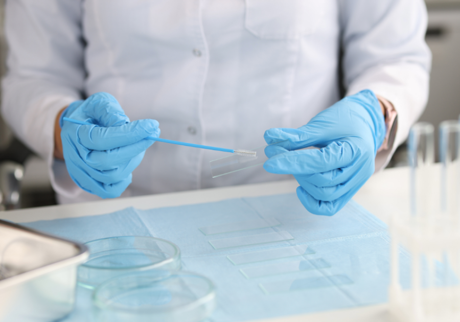 Doctor in gloves holds brush for smear and glass in lab. Credit: Canva/Alexander's images