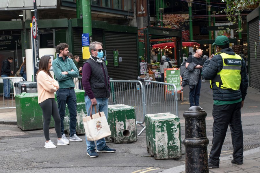 People standing in a queue, waiting to enter London&#039;s Borough Market which has been gated off by security.
