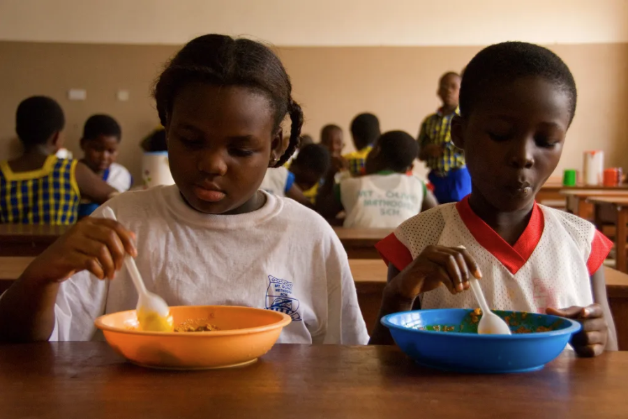 Two black children eat lunch at school from colourful bowls