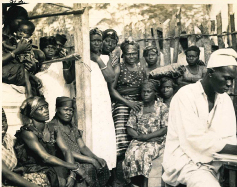 A man in the foreground wearing white while a group of people sit behind him