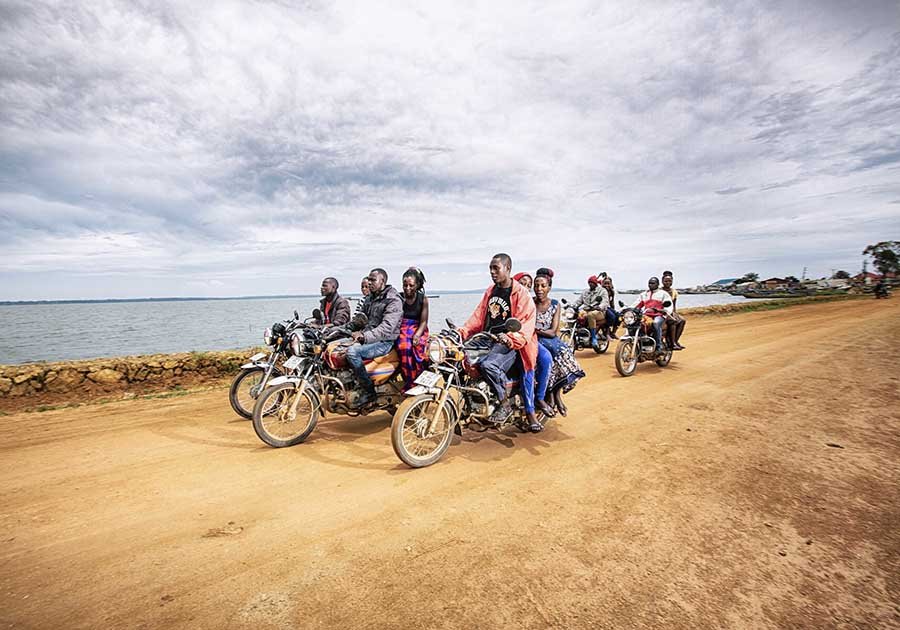 A group of people riding motorbikes along a dusty road
