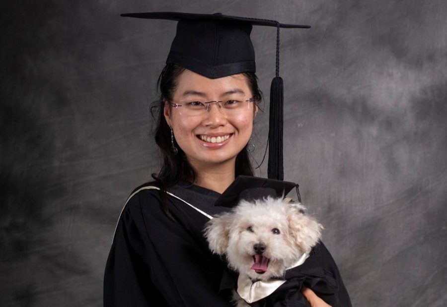 Norris Lau and her dog dressed in graduation gowns and hats