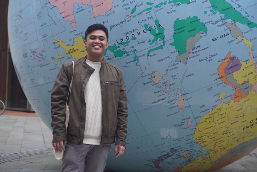 Student, Raymond, stood in front of a globe.