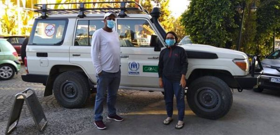 Ritu Rana and friend standing in front of a car wearing PPE