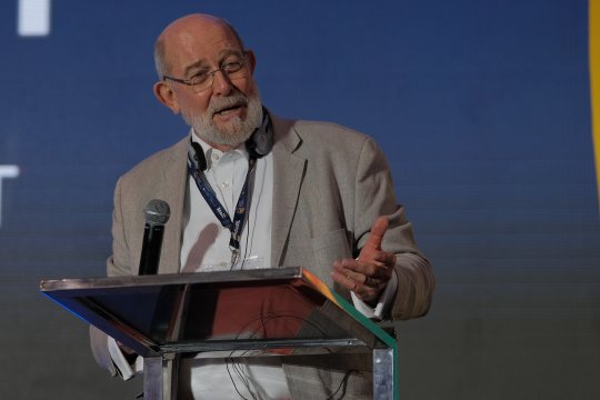 A man in grey suit speaks at a podium