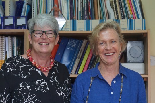 Ginny Bond and Helen Ayles standing and smiling in from of book shelves