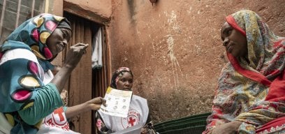 Red Cross volunteer speaks with a mother during community outreach