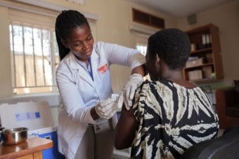 Nurse administering vaccine in arm of clinical trial participant in Uganda