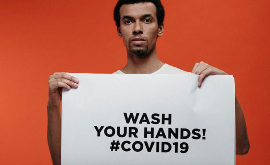 Man holding a sign reading: 'Wash your hands! #COVID19'